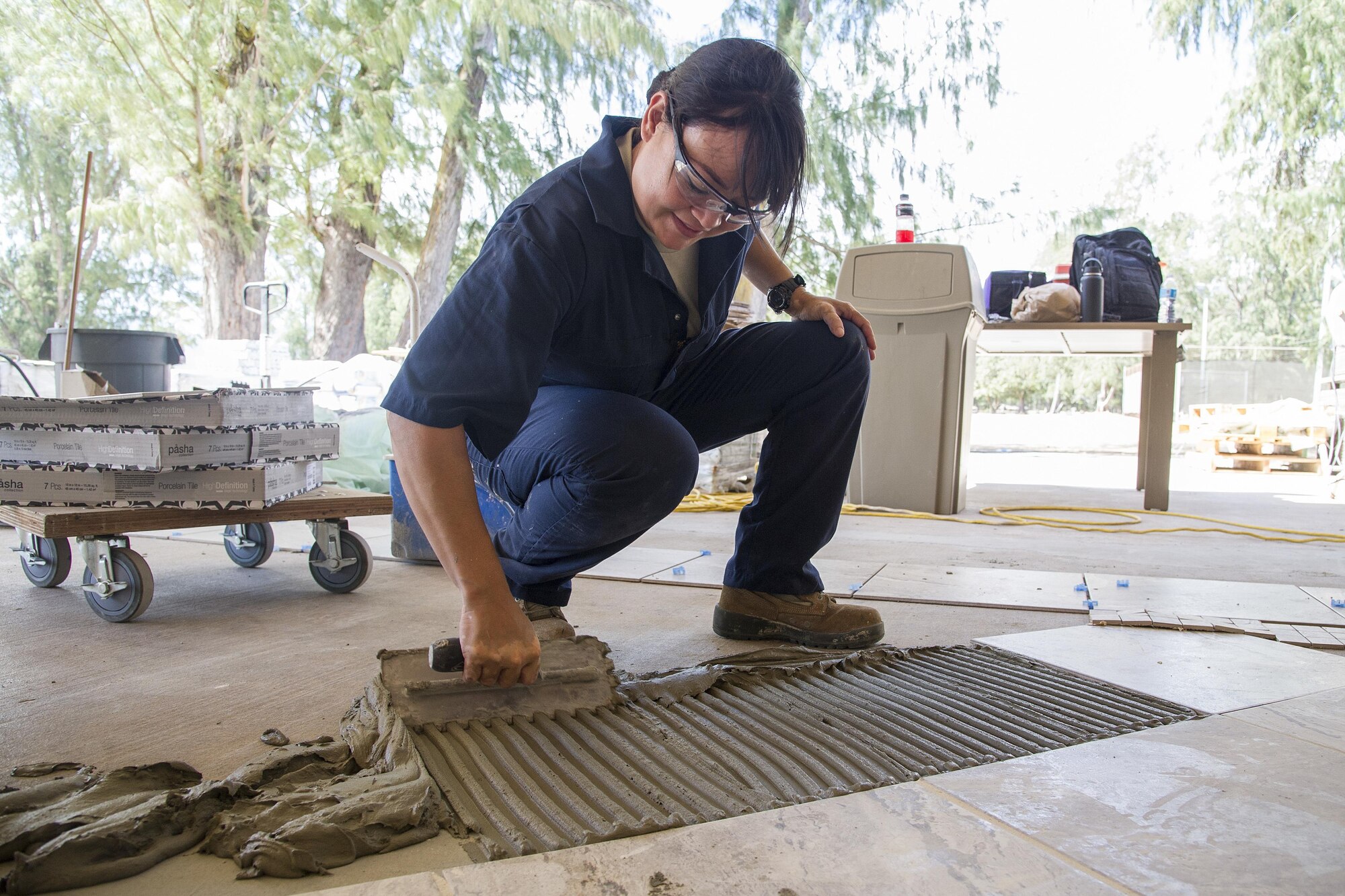 U.S. Air Force Senior Airman Veleesa Conley, of Wahiawa, Hawaii, a structural engineer with the Air Force Reserve’s 624th Civil Engineer Squadron, installs tile for the recreation center's 4,500-square-foot lanai at Bellows Air Force Station, Waimanalo, Hawaii, Aug. 25, 2017.