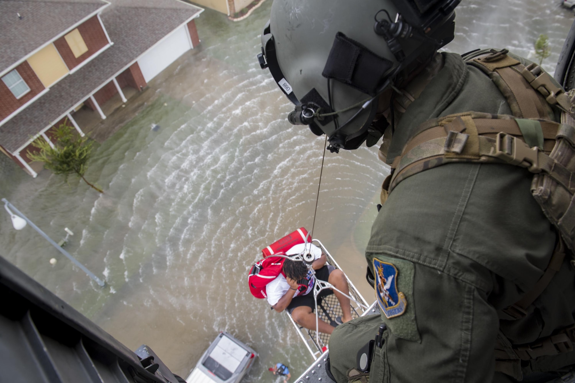 A special missions aviator from the 41st Rescue Squadron, watches as he raises an evacuee, Aug. 30, 2017, over a residence in the Houston, Texas area.