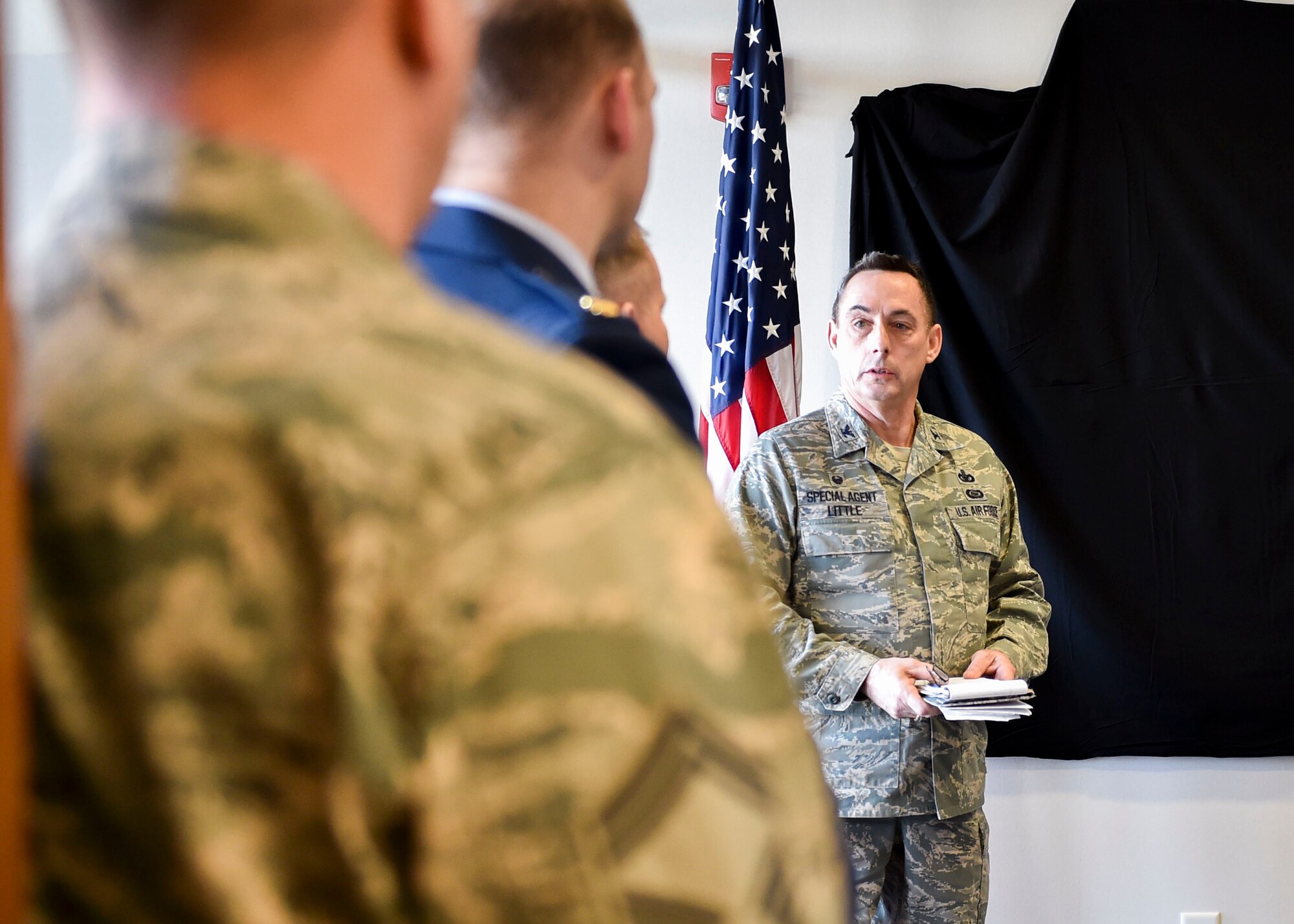 Special Agent John Driscoll, Air Force Office of Special Investigations (AFOSI) operating location chief here, gives opening remarks at a dedication ceremony for a memorial wall, Nov. 29, 2017