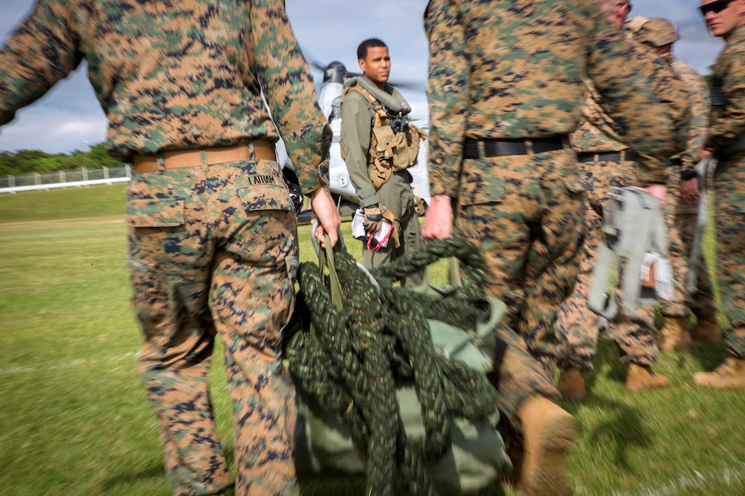 Marines carry a thick rope towards an MV-22B Osprey before participating in fast-rope training.