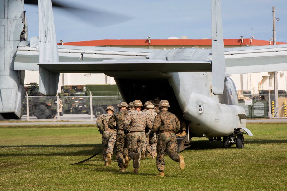 Marines rush aboard an MV-22B Osprey during fast-rope training.