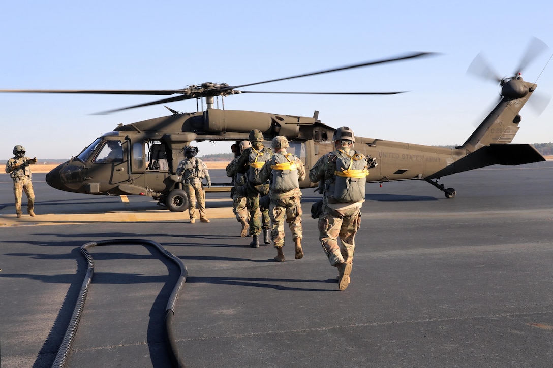 U.S. and Canadian army jumpmasters board a UH-60 Black Hawk helicopter for the 20th Annual Randy Oler Memorial Operation Toy Drop at Mackall Army Airfield, N.C.