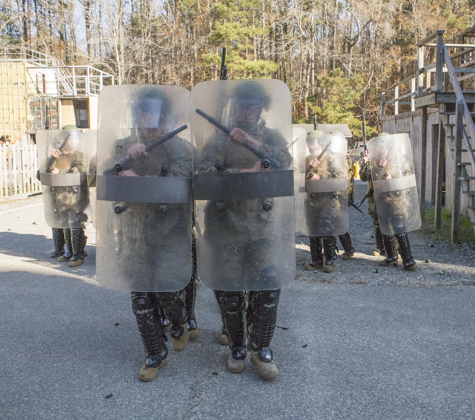 Marines from Basic Security Guard Course, Class 2-18, Training Co., U.S. Marine Corps Security Forces Regiment, move into a column formation during non-lethal tactics training at Munro Village, Naval Support Activity Northwest Annex, Chesapeake, Va., Nov. 30. Marines were required to demonstrate proficiency firing the M500 shotgun and the M203 grenade launcher while moving through the training area in full riot protection gear. (Official U.S. Marine Corps photo by Chris Jones/Released)