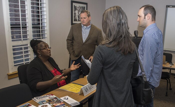 Tresia A. Frazer, left, vocational rehabilitation counselor, speaks with Staff Sgt. Robert Gibson, right, 628th Security Force Squadron and his wife Sadie Gibson as Bill Oldenburg, center, Education and Employment Initiative and Operational Warfighter regional coordinator – Mid-Atlantic, looks on during the Second Annual Warrior Care Breakfast and Information Fair at the Airman & Family Readiness Center here Nov. 29, 2017.