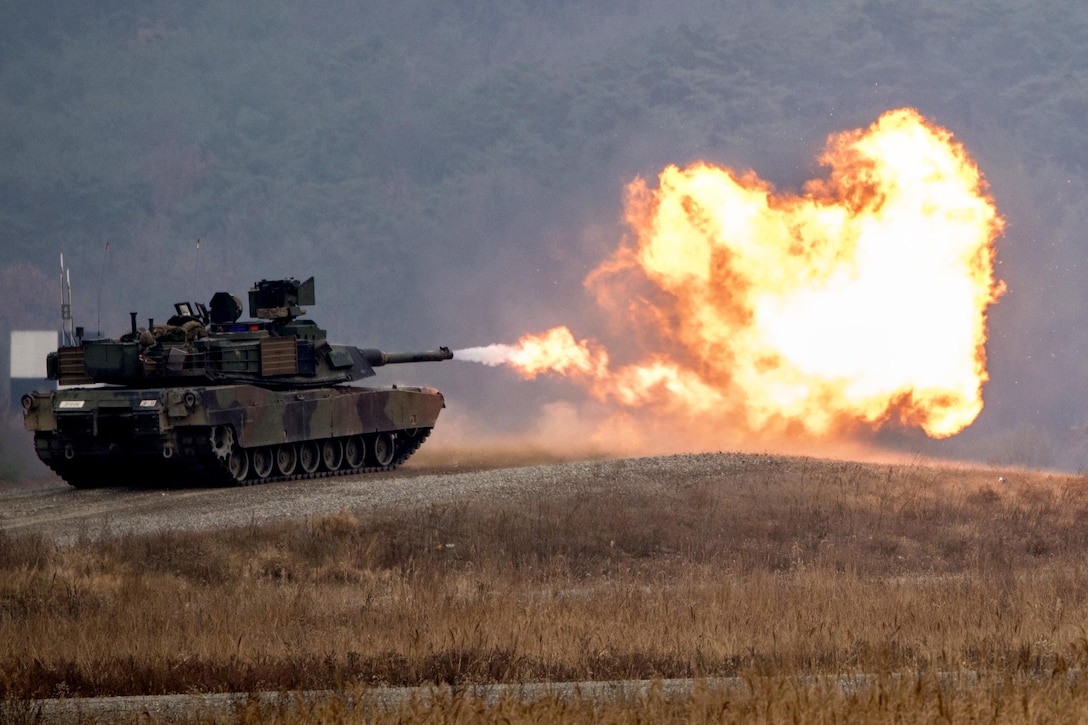 A fireball bursts out of a tank as it fires its main gun.