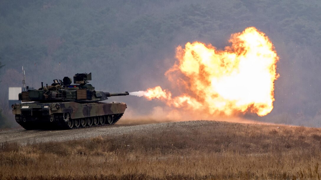 A fireball bursts out of a tank as it fires its main gun.