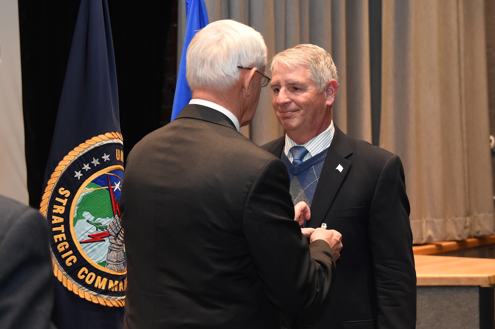 Patrick McVay (left), U.S. Strategic Command (USSTRATCOM) director of joint exercises, training and assessments, presents a retirement pin to Dr. William Astley, USSTRATCOM resiliency coordinator, during Astley’s retirement ceremony at Offutt Air Force Base, Neb., Nov. 30, 2017. Astley retired after 36-plus years of service as an Air Force officer and government civilian. Throughout his 11 years with USSTRATCOM, Astley led a team that developed several programs and activities to ensure members of the command remain sharp, fresh and productive. One of nine Department of Defense unified combatant commands, USSTRATCOM has global responsibilities assigned through the Unified Command Plan that include strategic deterrence, nuclear operations, space operations, joint electromagnetic spectrum operations, global strike, missile defense, and analysis and targeting.