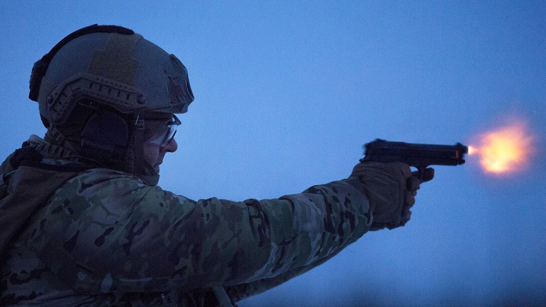 An airman fires a pistol.
