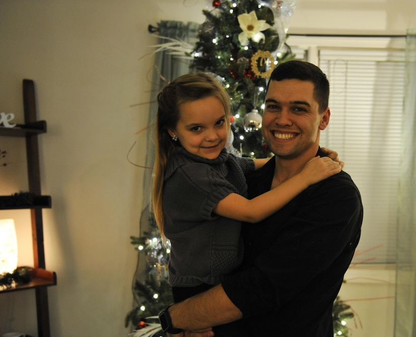 Senior Airman Ryan Deetman, 628th Logistics Readiness Squadron central storage journeyman, holds his daughter, Payslie Deetman, in front of a Christmas tree in their home at Joint Base Charleston, S.C., Nov. 30, 2017.