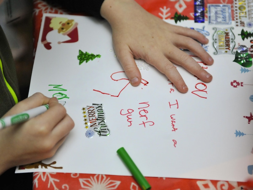 Mason, a child attending the holiday celebration, signs his letter to Santa at Joint Base Charleston – Weapons Station, S.C., Nov. 30, 2017.