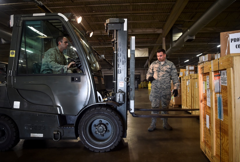 Senior Airman Zakary Keres, 437th Aerial Port Squadron air cargo services technician, directs Senior Airman Zachary Payne, 437th APS air cargo services technician, during a pallet build at Joint Base Charleston, S.C., Nov. 29, 2017.