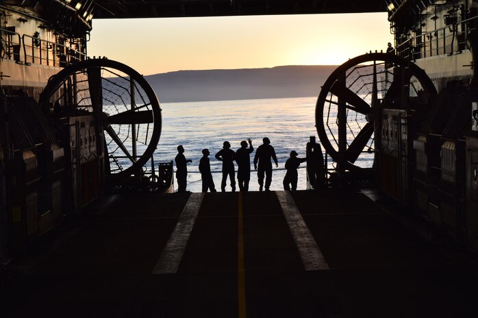 U.S. Navy landing craft, air cushion crew members with Assault Craft Unit 5 watch the sunrise off the western coast of San Clemente Island from the USS Anchorage well deck while preparing to conduct expeditionary advanced base operations during Exercise Dawn Blitz, Oct. 24, 2017. Dawn Blitz 17 provides an opportunity for collaboration between Navy and Marine Corps counterparts in the establishment of scalable and agile expeditionary advanced bases capable of expanding littoral maneuver capabilities.