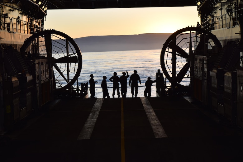 U.S. Navy landing craft, air cushion crew members with Assault Craft Unit 5 watch the sunrise off the western coast of San Clemente Island from the USS Anchorage well deck while preparing to conduct expeditionary advanced base operations during Exercise Dawn Blitz, Oct. 24, 2017. Dawn Blitz 17 provides an opportunity for collaboration between Navy and Marine Corps counterparts in the establishment of scalable and agile expeditionary advanced bases capable of expanding littoral maneuver capabilities.