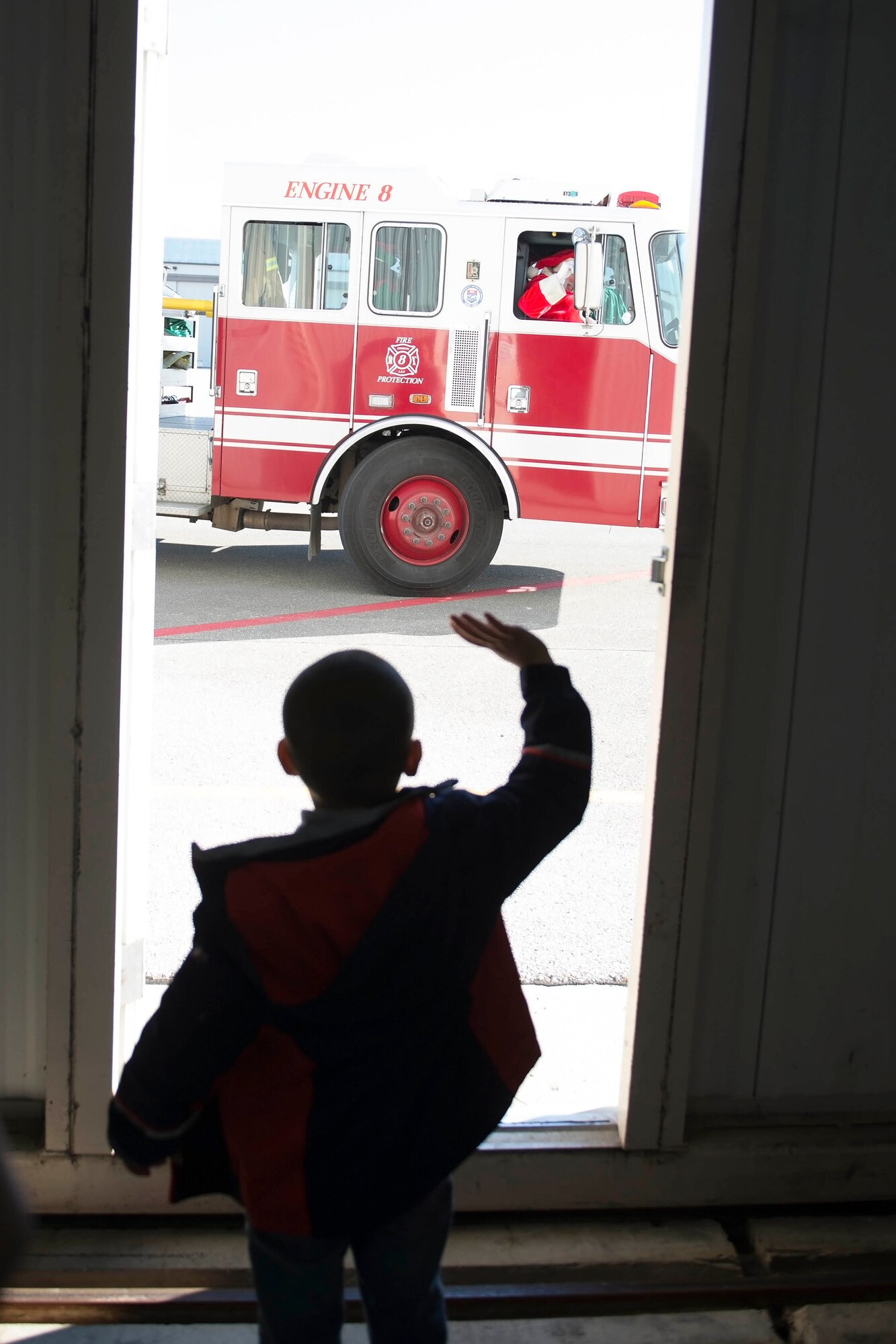 A young boy waives as santa and his helpers pull up in one of Grissom’s fire trucks. Santa’s arrival took place during Grissom’s Christmas childrens party here Dec. 2. (U.S. Air Force photo/Staff Sgt. Jami K. Lancette)