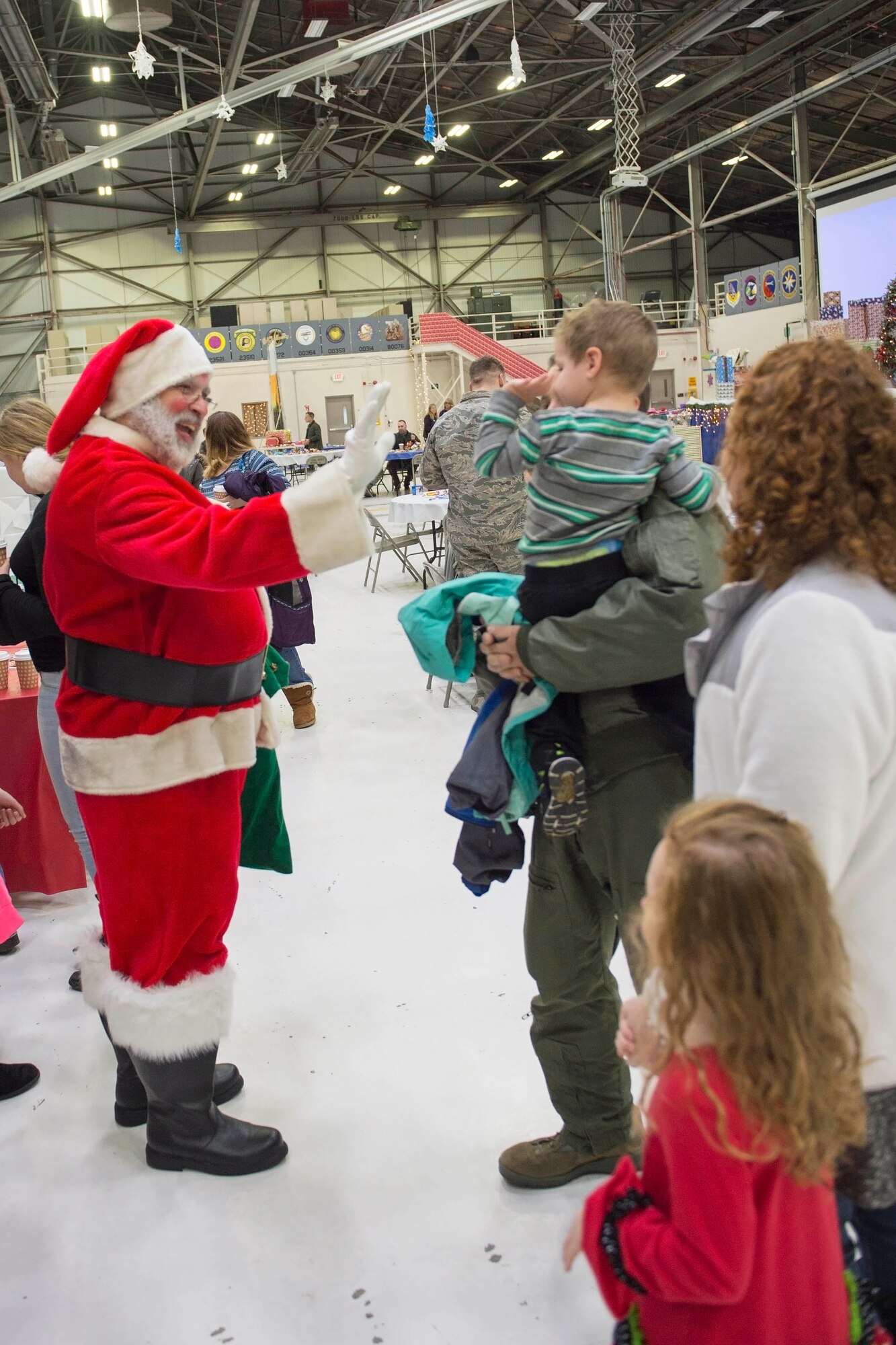 A young boy waives to santa and his helpers at a Christmas celebration. Santa’s arrival took place during Grissom’s Christmas childrens party here Dec. 2. (U.S. Air Force photo/Staff Sgt. Jami K. Lancette)