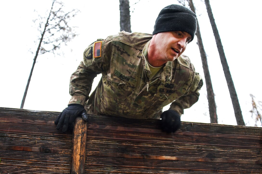 Army Maj. Mark Born jumps over a high-wall obstacle during the brigade’s first senior leader physical challenge.