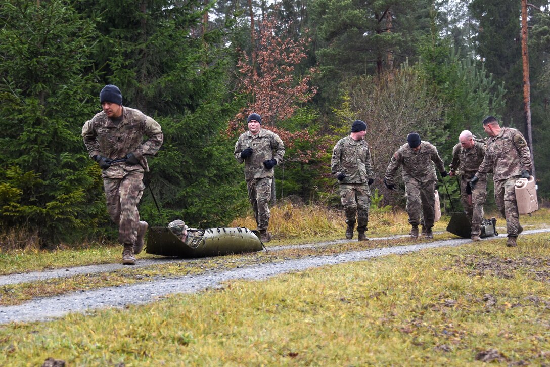 Soldiers drag mock casualties during a senior leader physical challenge.