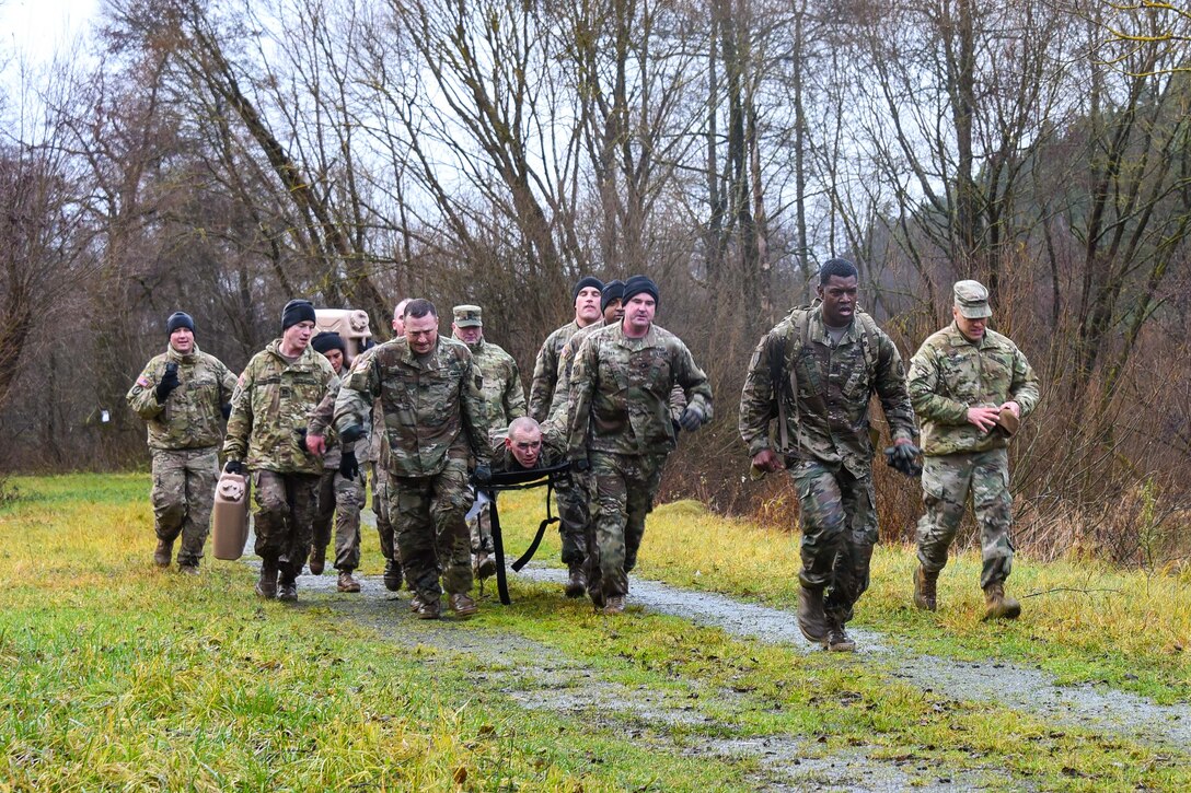 Soldiers run toward the finish line carrying a mock casualty.