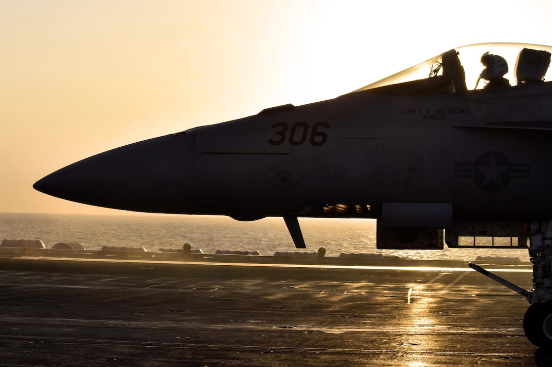 An F/A-18E Super Hornet aircraft taxis on the flight deck of an aircraft carrier.