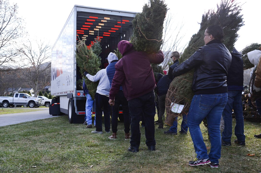 Guardsmen and family members help load Christmas trees onto trucks for troops.