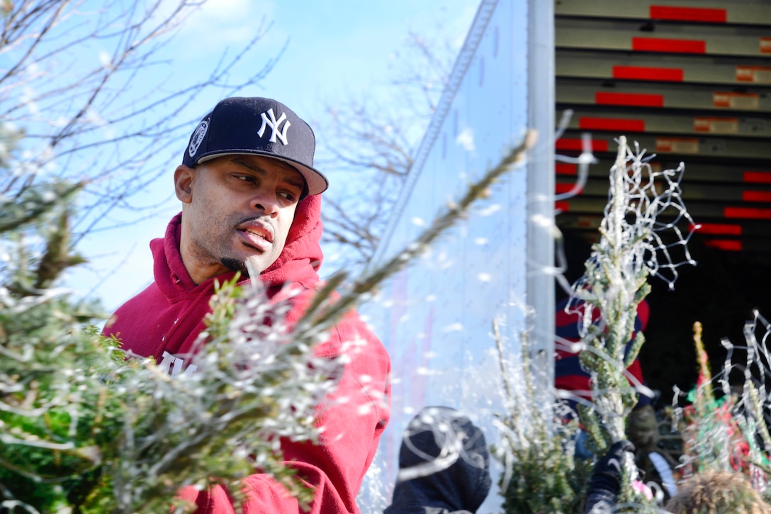 A New York Air National Guardsman helps load Christmas trees onto trucks for troops.