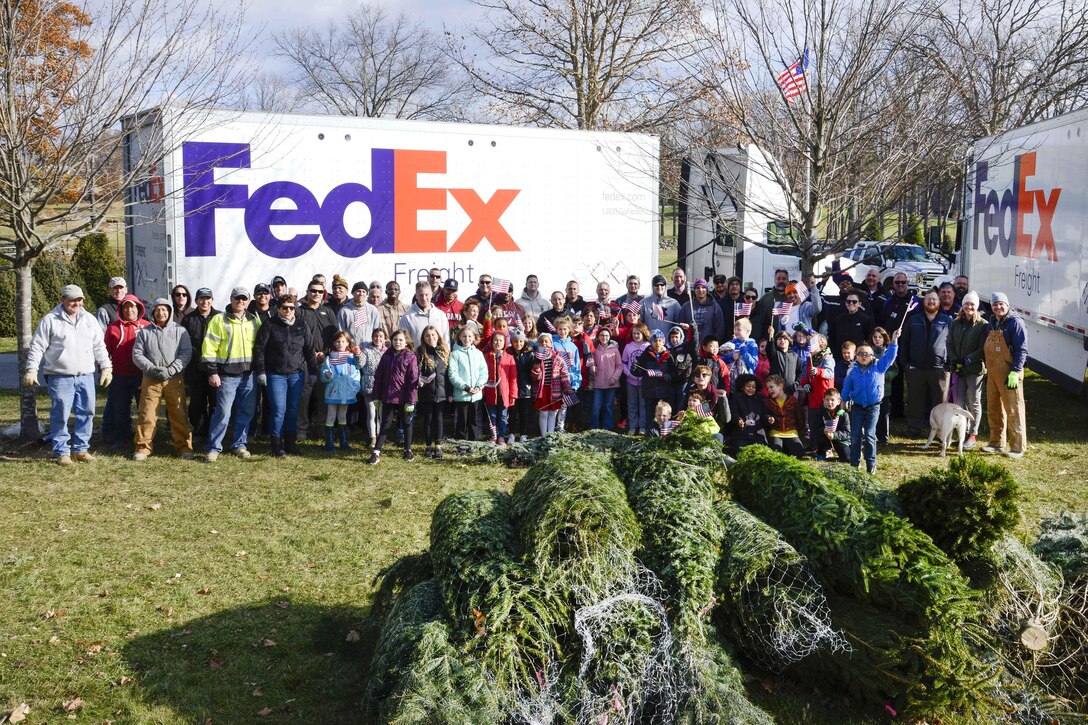 Guardsmen and family members pose for a photograph while volunteering to help load Christmas trees onto trucks for troops.