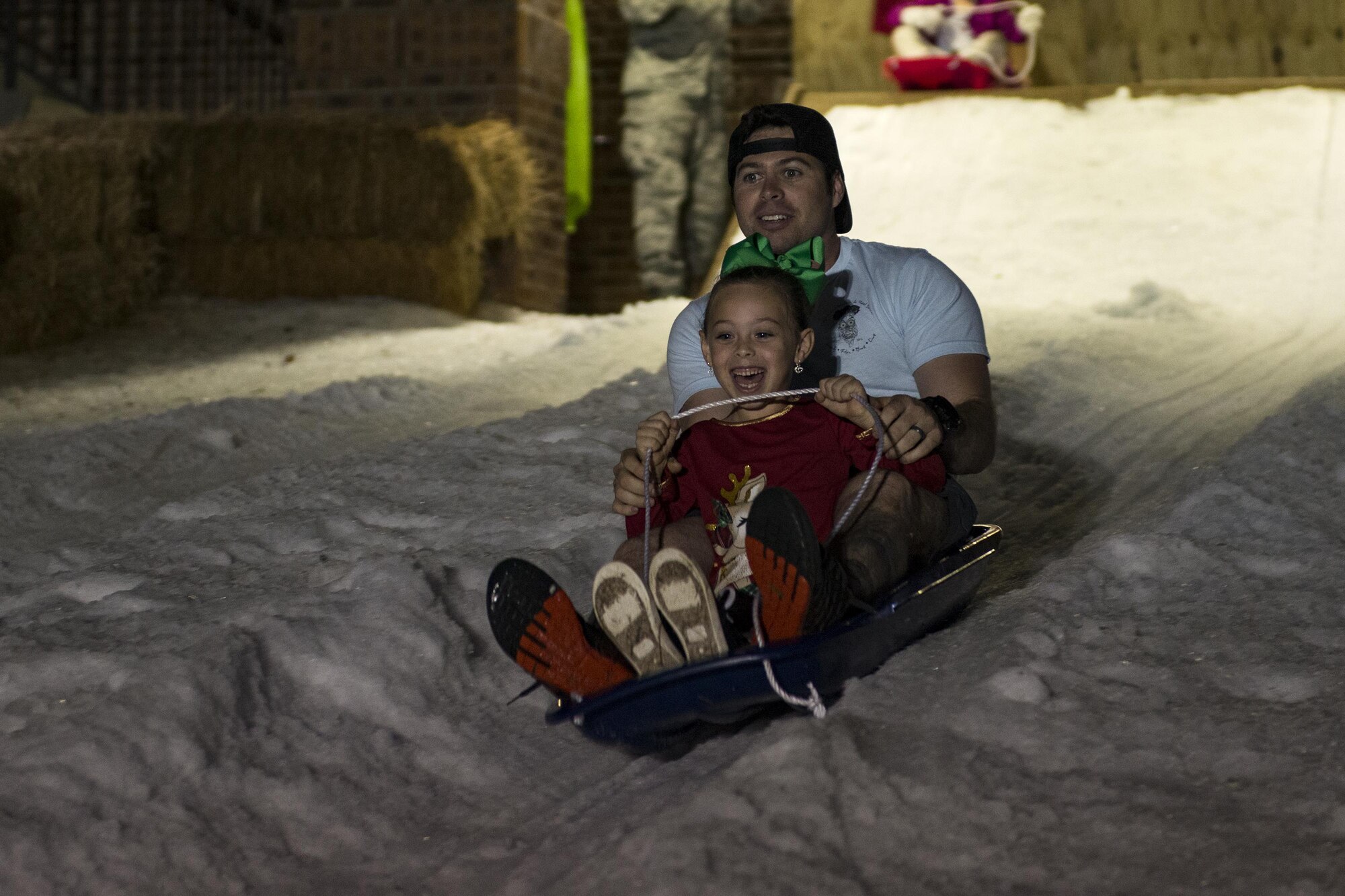Attendees sled down a hill during the Tree Lighting Ceremony, Dec. 1, 2017, at Moody Air Force Base, Ga. The annual event brings the base community together as a way to show thanks for their continuous sacrifice and celebrate the holiday season. The celebration included a parade, raffle give-a-ways, children’s activities and traditional lighting of the base Christmas tree by families of deployed Airmen. (U.S. Air Force photo by Airman 1st Class Erick Requadt)