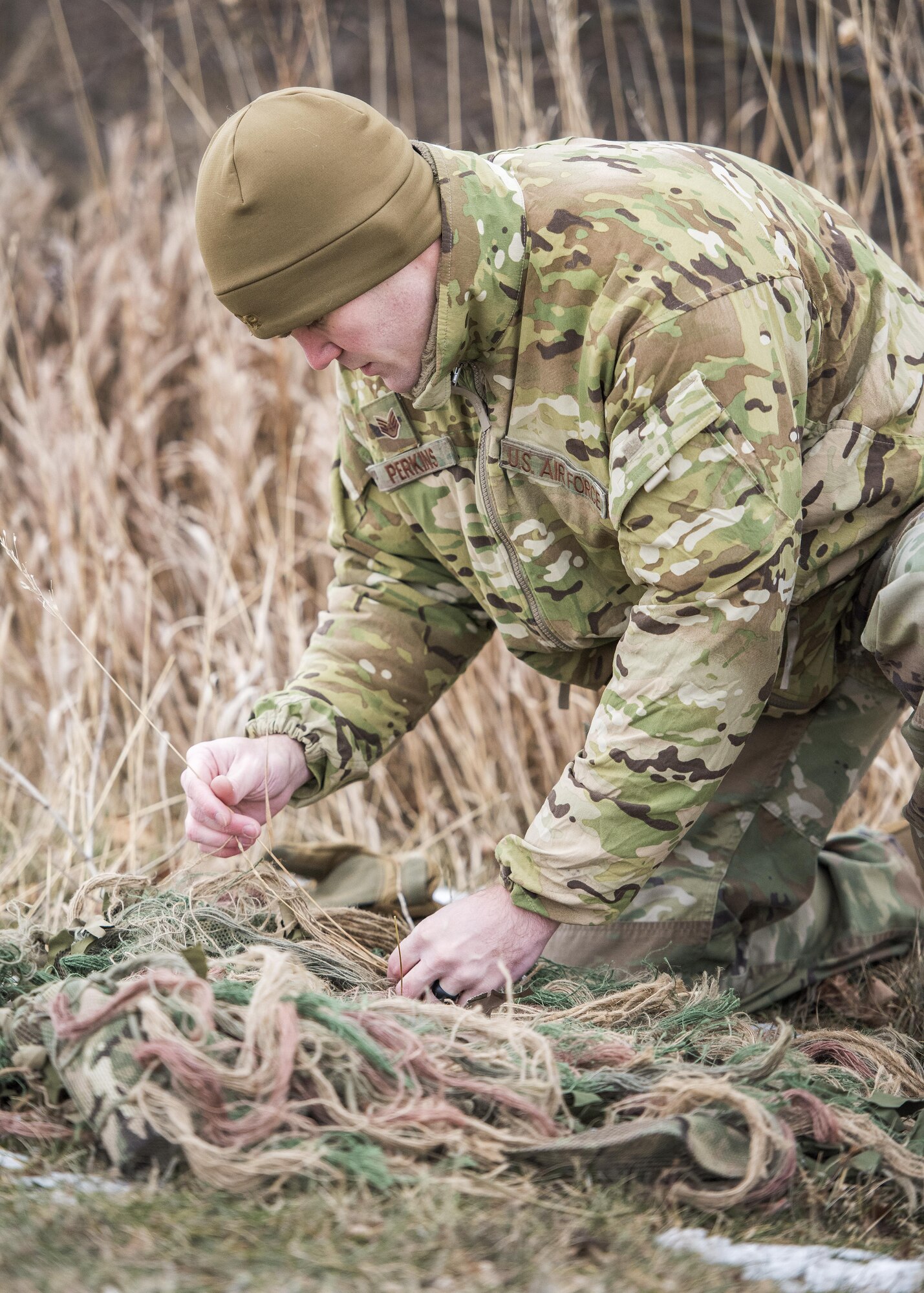 Staff Sgt. Bryan Perkins, 791st Missile Security Forces Squadron defender, sews foliage on to his ghillie suit during joint-unit training at Minot Air Force Base, N.D., Nov. 22, 2017. During training, Airmen added natural elements such as sticks and grass to their camouflage suits to better integrate themselves in a variety of locations. (U.S. Air Force photo by Senior Airman J.T. Armstrong)