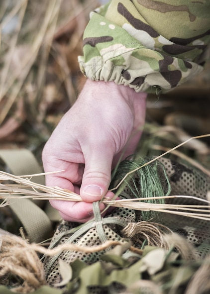 Staff Sgt. Bryan Perkins, 791st Missile Security Forces Squadron defender, sews foliage on to his ghillie suit during joint-unit training at Minot Air Force Base, N.D., Nov. 22, 2017. During training, Airmen added natural elements such as sticks and grass to their camouflage suits to better integrate themselves in a variety of locations. (U.S. Air Force photo by Senior Airman J.T. Armstrong)