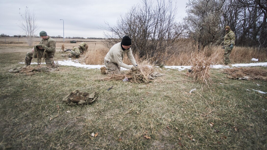 Defenders from the 791st Missile Security Forces Squadron sew foliage on to their ghillie suits during joint-unit training at Minot Air Force Base, N.D., Nov. 22, 2017. During training, Airmen added natural elements such as sticks and grass to their camouflage suits to better integrate themselves in a variety of locations. (U.S. Air Force photo by Senior Airman J.T. Armstrong)