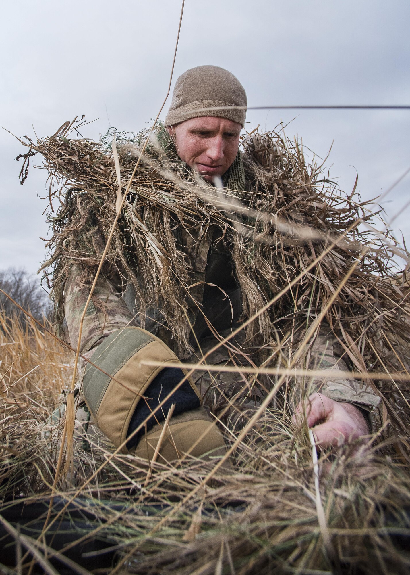 Senior Airman Joshua Roberts, 791st Missile Security Forces Squadron defender, ties foliage to his uniform during joint-unit training at Minot Air Force Base, N.D., Nov. 22, 2017. During training, 791 MSFS defenders camouflaged themselves and evaded capture by the 5th Security Forces Squadron K9 team to prepare both units for situations deployed locations. (U.S. Air Force photo by Senior Airman J.T. Armstrong)