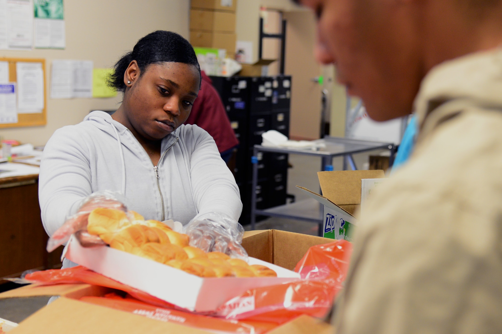 Airman 1st Class Destini Vance, 341st Force Support Squadron customer support apprentice, pulls rolls out of a box during Meals on Wheels meal preparation Nov. 22, 2017, in Great Falls, Mont. Food is divided into single-person servings for proper nutrition. (U.S. Air Force photo by Airman 1st Class Tristan Truesdell)