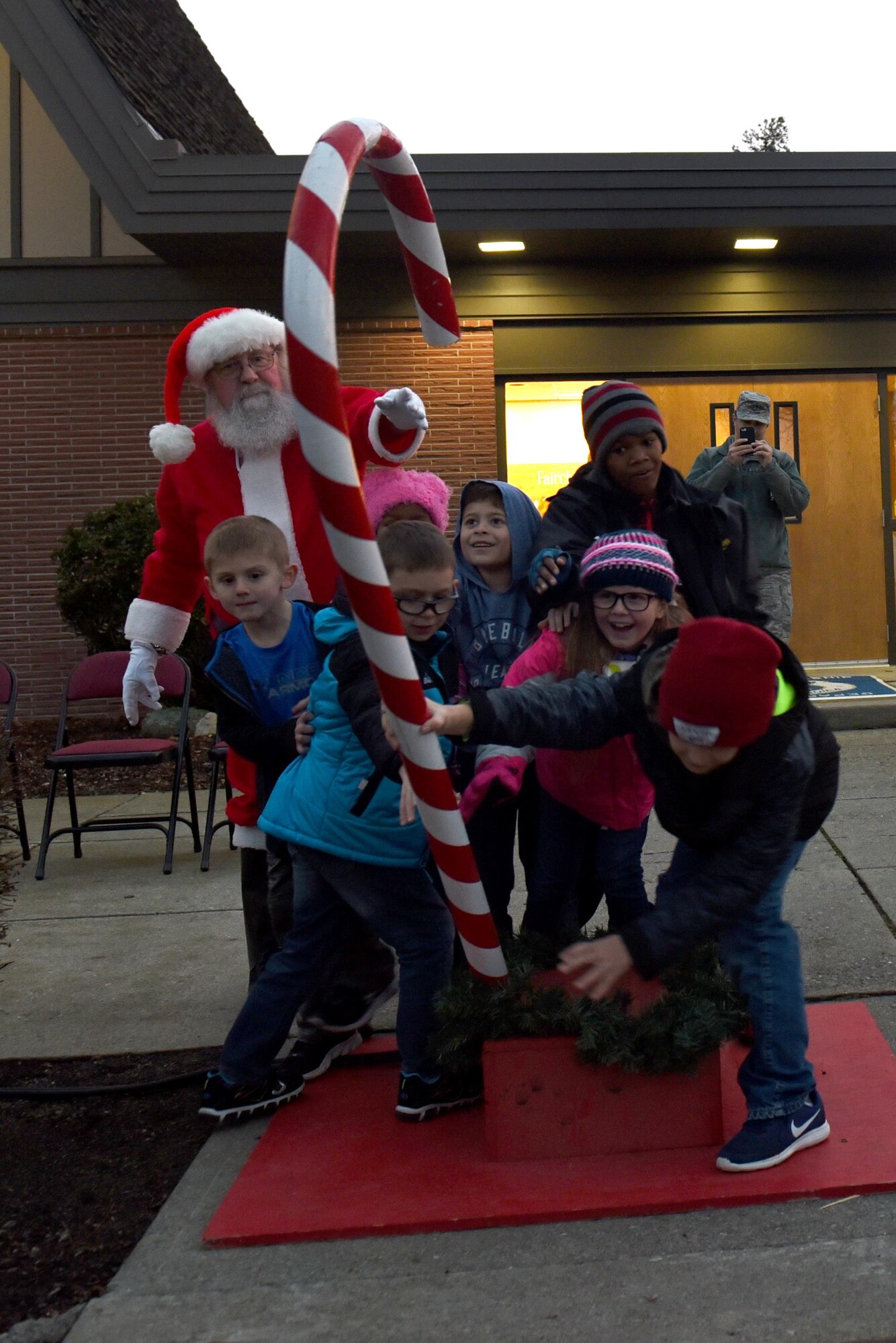 Santa Claus helps children of deployed members light the holiday tree during the annual Holiday Tree Lighting Ceremony Dec.1, 2017, at Fairchild Air Force Base, Washington. During the ceremony, Santa joined Team Fairchild and their families at the base chapel for holiday caroling, cookies and hot chocolate. (U.S. Air Force photo/Airman Whitney Laine)