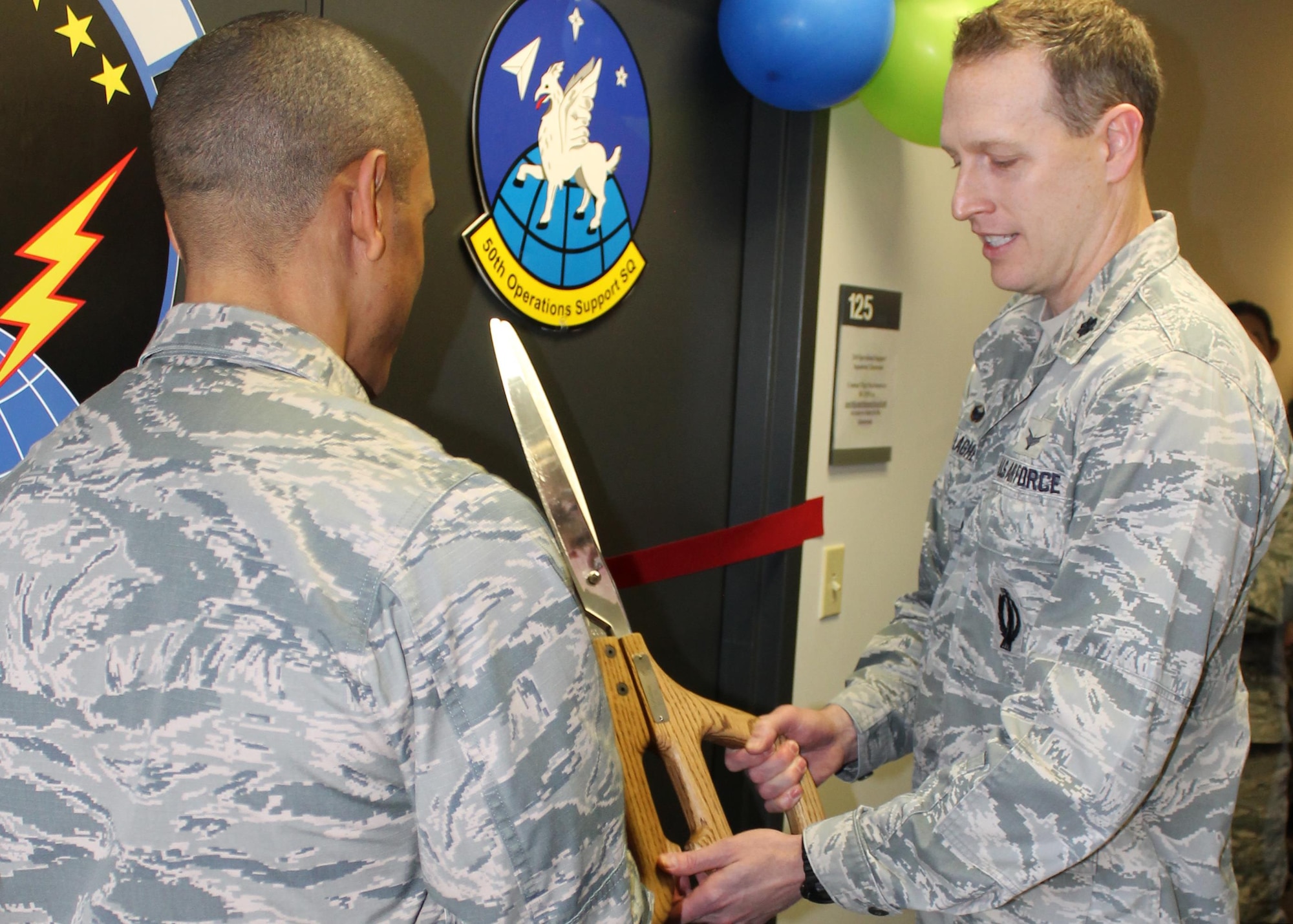 Lt. Col. David Gallagher, 50th Operations Support Squadron commander, and Lt. Col. Kelvin Dumas, 310th OSS commander, prepare to cut the ribbon marking the opening of their new training classroom dubbed 'The Hornet's Nest' on Friday, Dec. 1st, 2017.