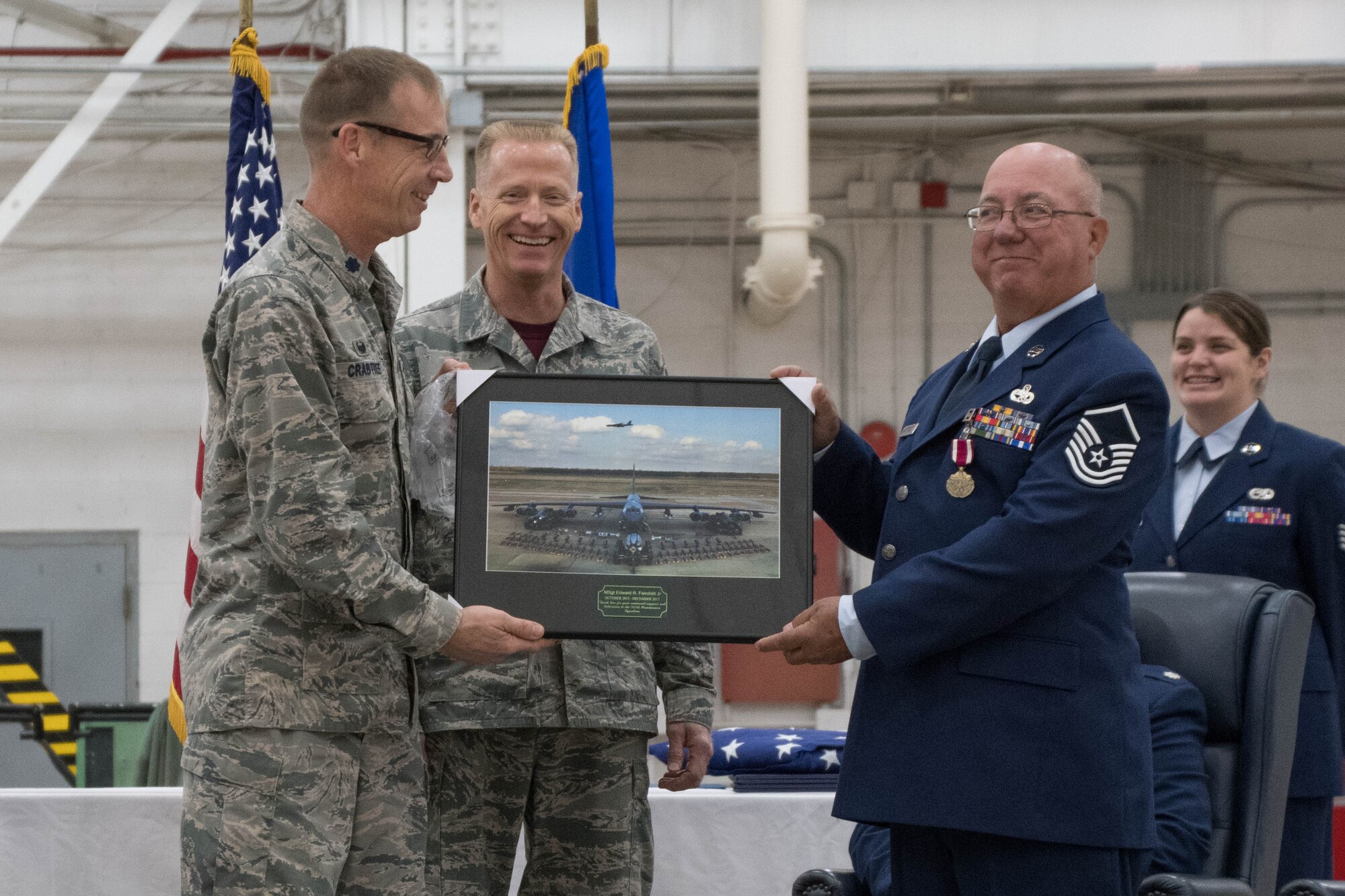 U.S. Air Force Lt. Col. Warren Crabtree, 707th Maintenance Squadron commander, and Chief Master Sgt. Scott Moeller, 707th MXS superintendent, present Master Sgt. Edward Fairchild, 707th MXS aircraft technician expeditor, with a personalized photo of a B-52 Stratofortress during a retirement ceremony on Barksdale Air Force Base, La., Dec. 2, 2017.