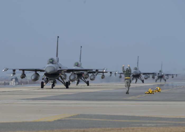 A U.S. Air Force Airman signals an F-16 Fighting Falcon pilot participating in an elephant walk to test the 8th Fighter Wing’s ability to generate combat ready aircraft during exercise VIGILANT ACE 18 on Dec. 3, 2017, at Kunsan Air Base, Republic of Korea. Airmen at Kunsan supported the regularly scheduled week-long exercise, which featured 12,000 U.S. personnel working alongside members of the Republic of Korea Air Force at eight U.S. and ROK military installations. (U.S. Air Force photo by Senior Airman Colby Hardin)