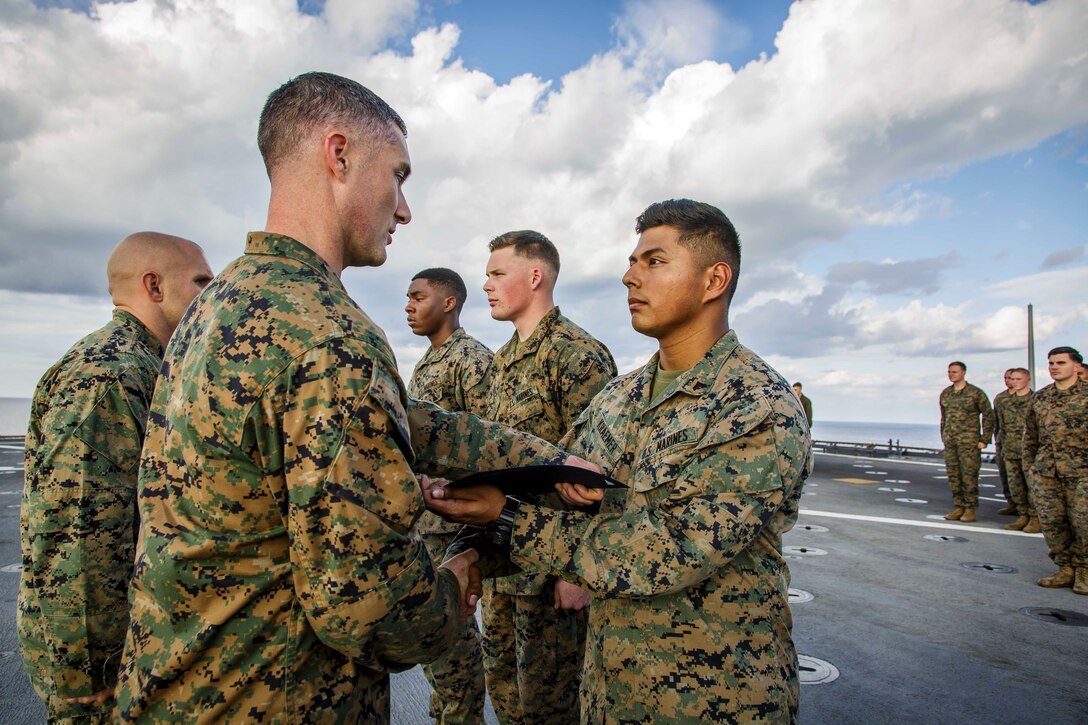 U.S. Marine Corps Cpl. Hunter S. Kraemer, right, an assault amphibious vehicle commander with Fox Company, Battalion Landing Team, 2nd Battalion, 6th Marine Regiment, 26th Marine Expeditionary Unit (MEU), receives his promotion warrant from Capt. Joseph Murphy, left, commanding officer of Fox Co., BLT/2/6, 26th MEU, during a ceremony aboard the dock landing ship USS Oak Hill (LSD 51) in the Atlantic Ocean, Dec. 1, 2017, during Combined Composite Training Unit Exercise (COMPTUEX). Combined COMPTUEX allows all elements of the Marine Air Ground Task Force to join and train in realistic scenarios so the MEU as a whole can meet its Predeployment Training Program objectives prior to an upcoming deployment at sea. (U.S. Marine Corps photo by Staff Sgt. Dengrier M. Baez)