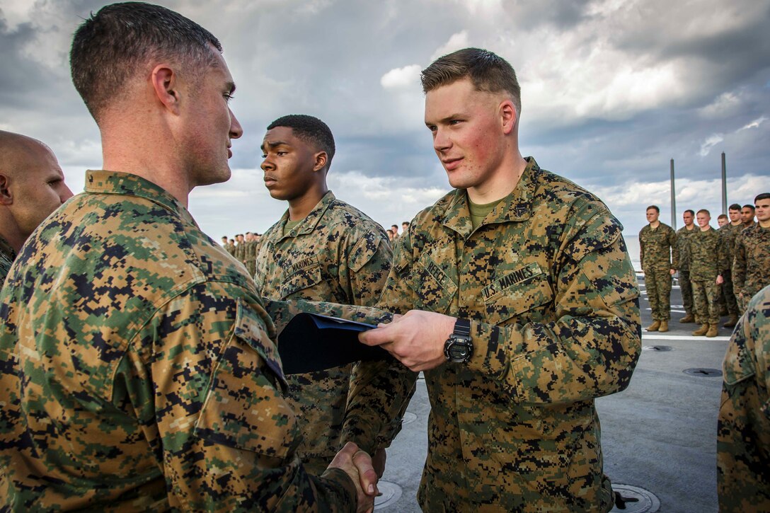 U.S. Marine Corps Cpl. Zachery R. Reece, right, a fire support Marine with Fox Company, Battalion Landing Team, 2nd Battalion, 6th Marine Regiment, 26th Marine Expeditionary Unit (MEU), receives his promotion warrant from Capt. Joseph Murphy, left, commanding officer of Fox Co., BLT/2/6, 26th MEU, during a ceremony aboard the dock landing ship USS Oak Hill (LSD 51) in the Atlantic Ocean, Dec. 1, 2017, during Combined Composite Training Unit Exercise (COMPTUEX). Combined COMPTUEX allows all elements of the Marine Air Ground Task Force to join and train in realistic scenarios so the MEU as a whole can meet its Predeployment Training Program objectives prior to an upcoming deployment at sea. (U.S. Marine Corps photo by Staff Sgt. Dengrier M. Baez)