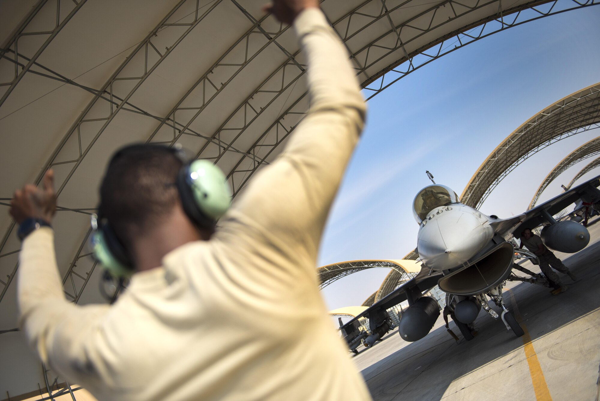 Senior Airman Jamichael Rainge, 407th Expeditionary Aircraft Maintenance Squadron crew chief, directs an F-16 Fighting Falcon pilot from the 100th Fighter Squadron into position for recovery following a combat sortie in support of Operation Inherent Resolve November 20, 2017, in an undisclosed location. The 100th FS provides close-air support and defensive counter-air capabilities to assist coalition forces on the ground. (U.S. Air Force photo by Staff Sgt. Joshua Kleinholz)