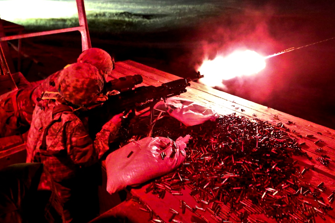 Spcs. Timothy Dauser and Christopher Landon work together as gunner and assistant gunner to qualify on an M240B machine gun.