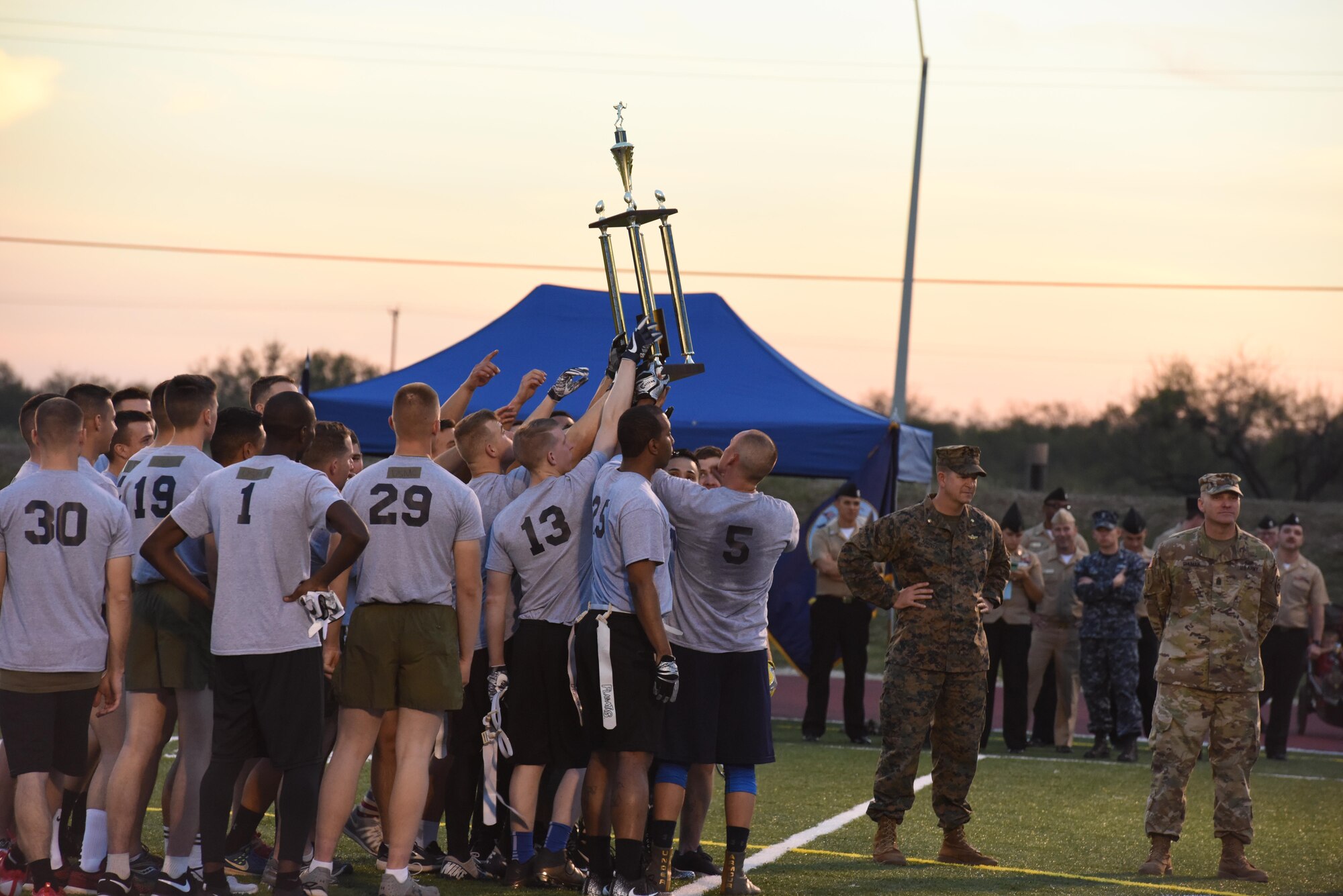 U.S Navy and Marines join around the trophy after winning the Army-Navy game at the Mathis Fitness Center field Dec. 1. This is the Navy’s second win in 14 years. (U.S. Air Force photo by Airman 1st Class Zachary Chapman/Released)
