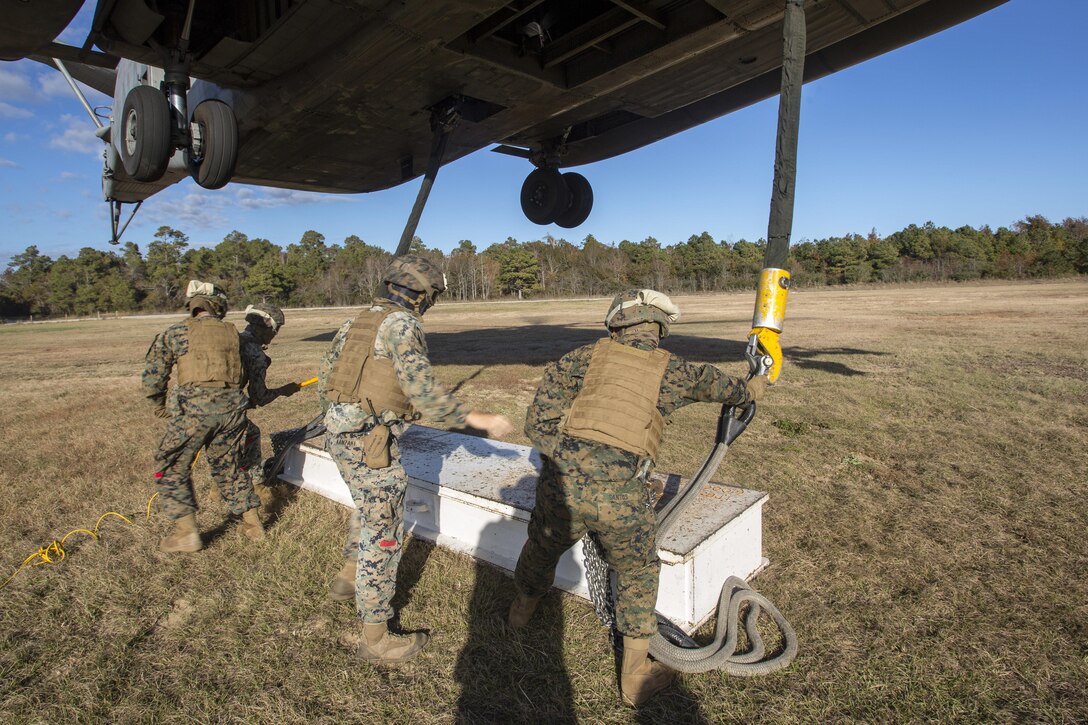 Marines with Combat Logistics Battalion 6, 2nd Marine Logistics Group attach cables and practice materials to a CH-53E Super Stallion during Helicopter Support Team training at Camp Lejeune, N.C., Nov. 28, 2017. A Helicopter Support Team is comprised of approximately eight landing support specialist Marines who ensure the equipment is properly attached and secured before pilots transport the gear or supplies to their destination. (U.S. Marine Corps photo by Cpl. Aaron Henson)