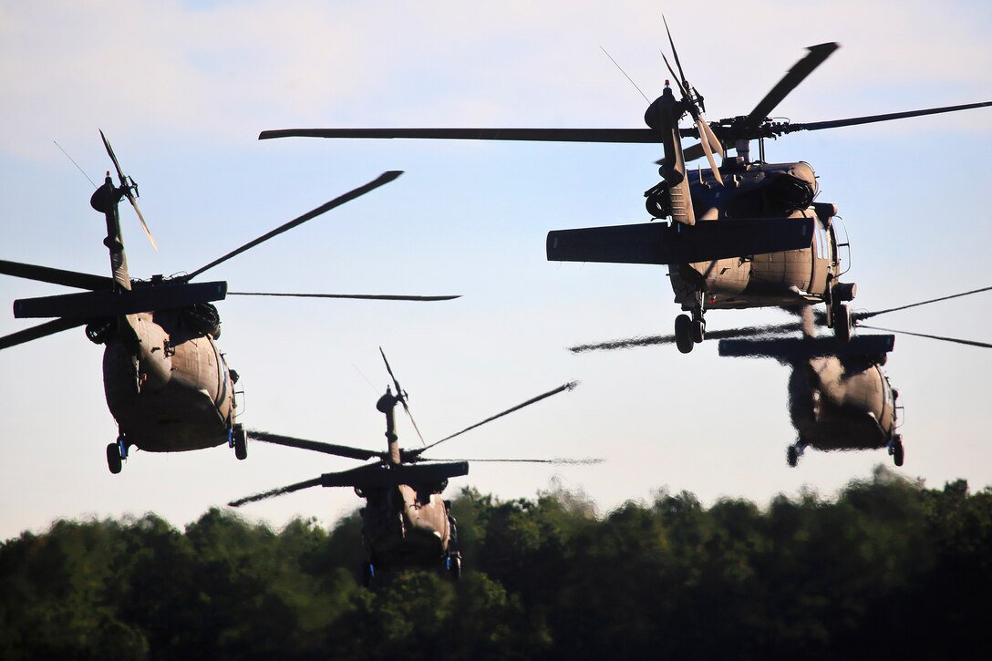 Four UH-60 Black Hawk helicopters take off in a multi-ship formation before participating in a training exercise.