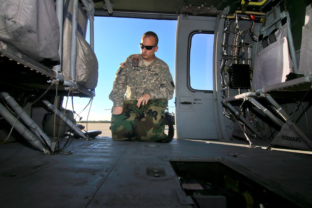 Army Warrant Officer I Adam Siegman gets his gear ready inside a Black Hawk helicopter before a training exercise.