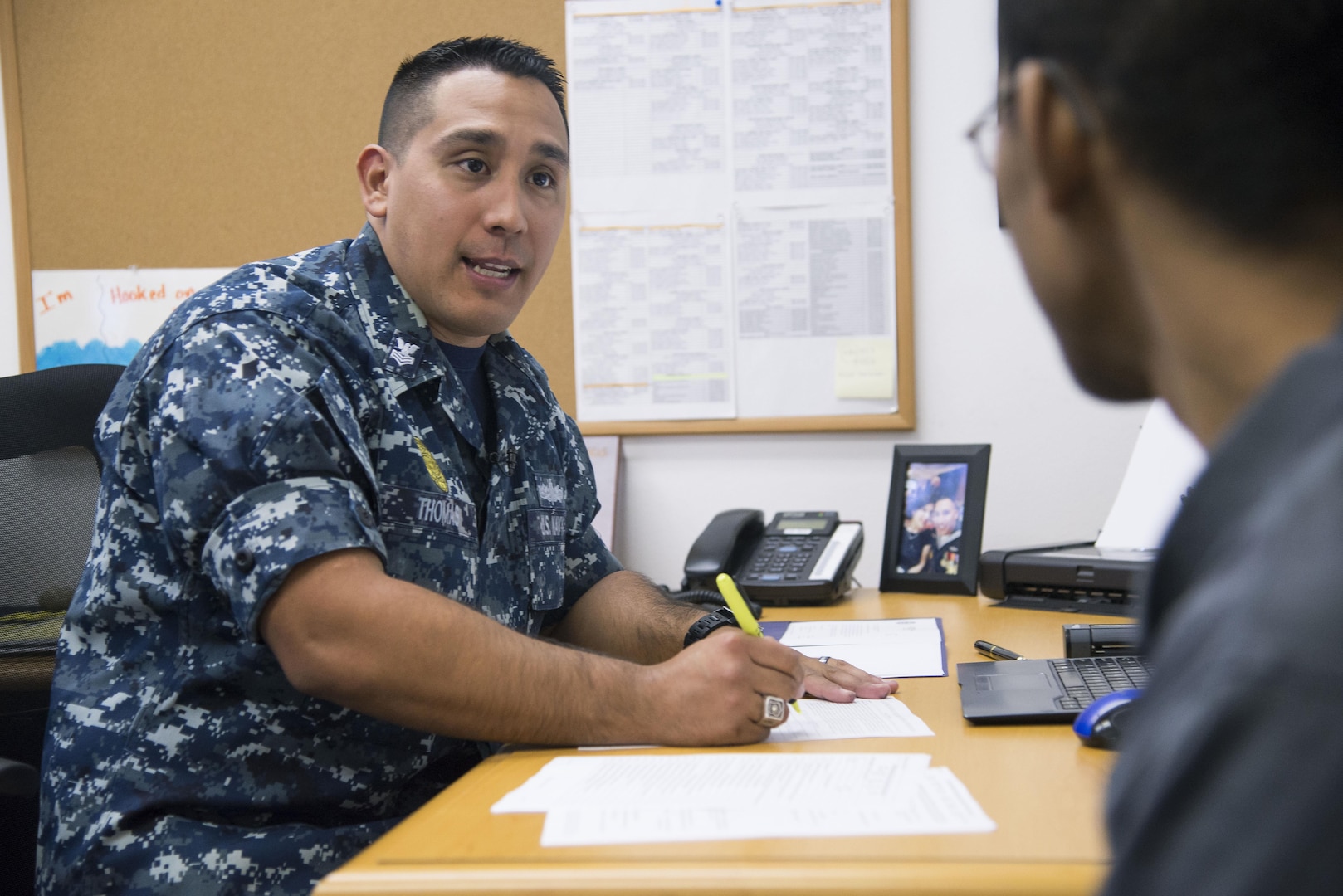 Petty Officer First Class Christopher Thomas, Navy Recruiting District San Antonio recruiter, speaks to an applicant about job opportunities in the Navy Oct. 25, 2017.  Thomas’ mission is to find officer applicants to lead naval forces in conducting operations on land, air and sea.  (U.S. Air Force photo by Sean M. Worrell)