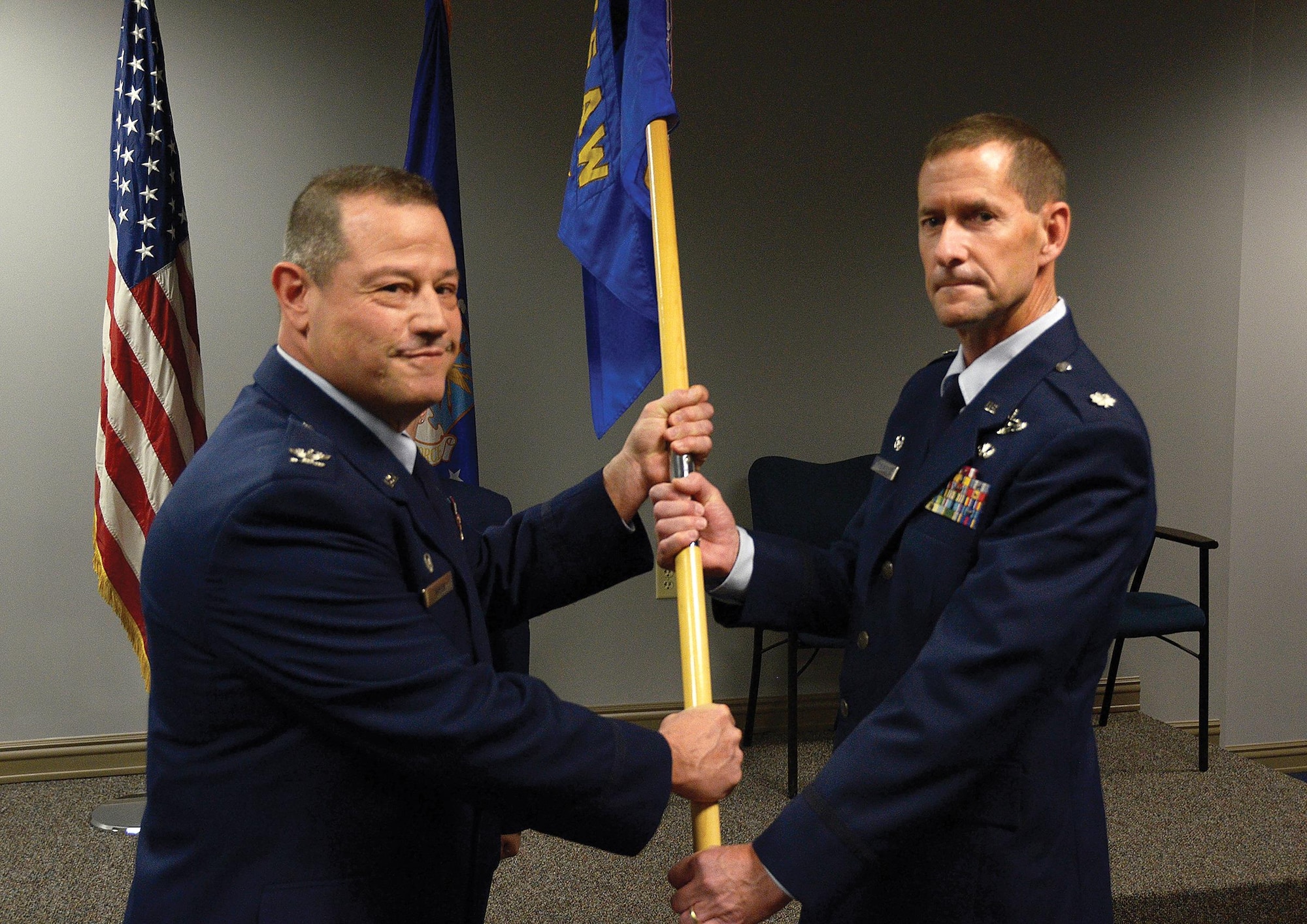 Col. Adam Willis, 445th Airlift Wing commander, passes the guidon to Lt. Col. John Robinson, incoming 445th Operations Group commander at the OG assumption of command ceremony, Nov. 5, 2017.