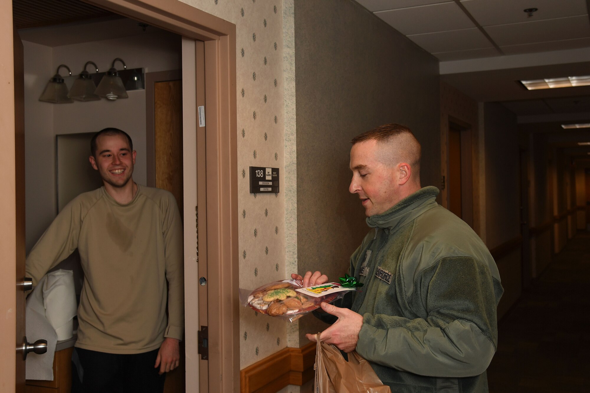 Master Sgt. Scott Harris, first sergeant with the 319th Logistics Readiness Squadron, right, delivers a plate of cookies to Airman 1st Class Austin Erickson, lodging assistant with the 319th Force Support Squadron, during the annual cookie drive on Grand Forks Air Force Base, N.D., on Dec. 4, 2017. Erickson is one of the hundreds of Airmen living in the dorms who each received a plate of treats donated by members of the Spouses Club on base and the local community. (U.S. Air Force photo by Elora J. Martinez)