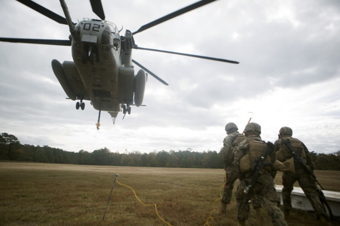 Marines with Combat Logistics Battalion 22 prepare to hook a weighted gear box to a CH-53E Super Stallion for an external lift during helicopter support team training at Camp Lejeune, N.C., Nov. 21, 2017. The training prepares Marines to provide expedient transportation of gear and supplies to units in locations not suited for ground transportation. (U.S. Marine Corps Photo by Pfc. Heather Atherton)