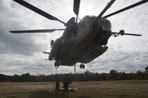 Marines with Combat Logistics Battalion 22 prepare to hook a weighted gear box to a CH-53E Super Stallion for an external lift during helicopter support team training at Camp Lejeune, N.C., Nov. 21, 2017. The training prepares Marines to provide expedient transportation of gear and supplies to units in locations not suited for ground transportation. (U.S. Marine Corps Photo by Pfc. Heather Atherton)