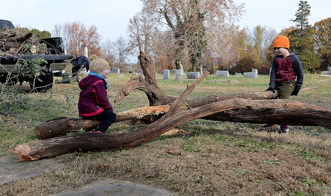 Anna Myers, age three, and Finnigan Myers, age six, children of U.S. Army Lt. Col. Vince Myers, McDonald Army Health Center commander, use a log as a seesaw during a restoration project at Pleasant Shade Cemetery in Hampton, Va. Dec. 2, 2017.